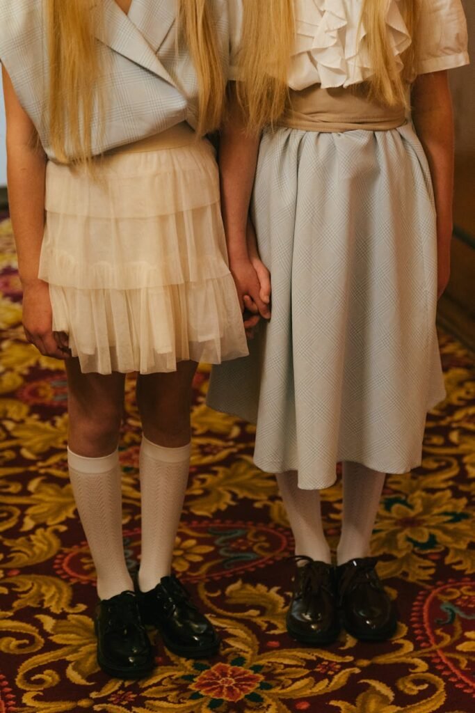 close up of blonde girls in skirts standing together and holding hands